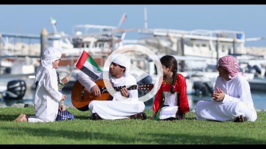 Middle Eastern siblings sitting on the grass celebrating the UAE National Day|