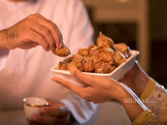 Woman serving Arabic sweets|-