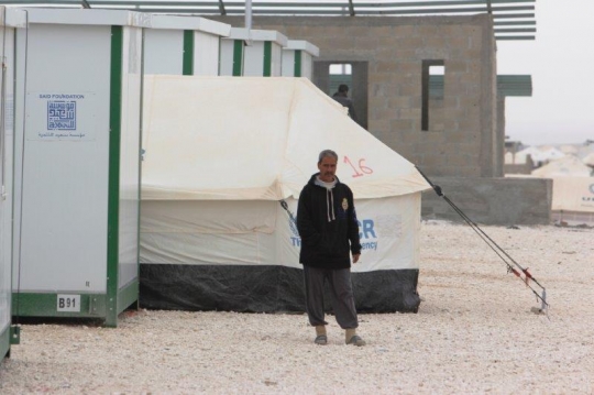 man standing next to mansion in refugees camp