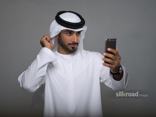 Arab man fixing his ghutra taking a selfie|