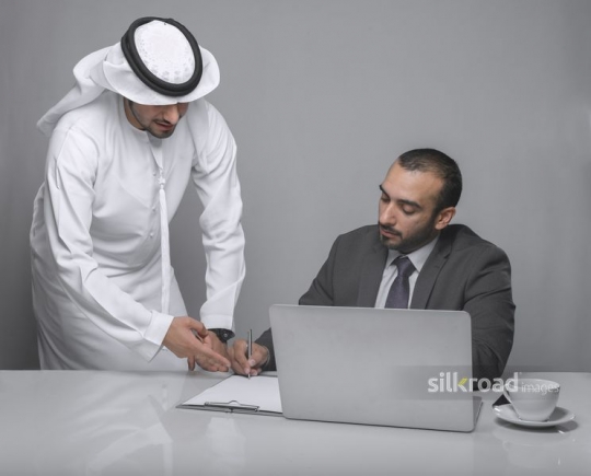 Middle Eastern man signing documents with colleague|