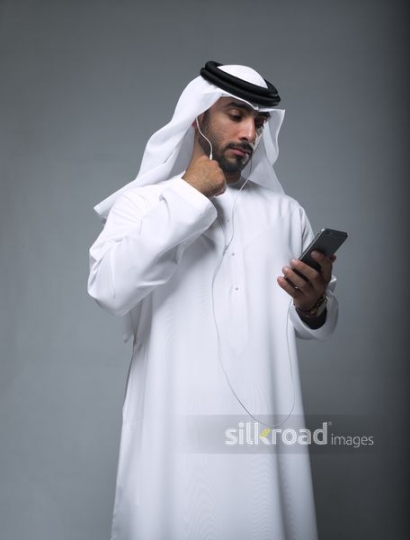 Arab man listening through his earphones|