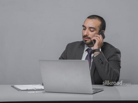 Businessman speaking over the phone while working|