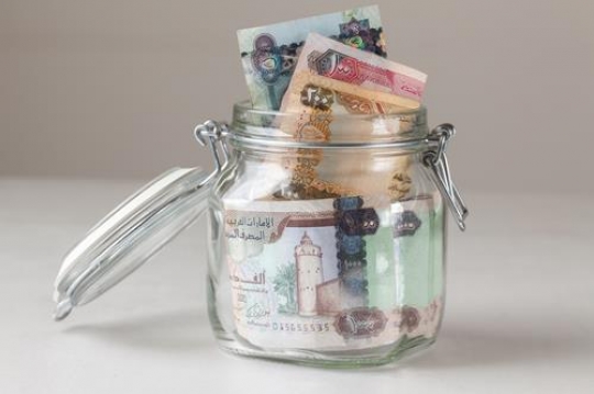 a glass jar filled with uae dirhams