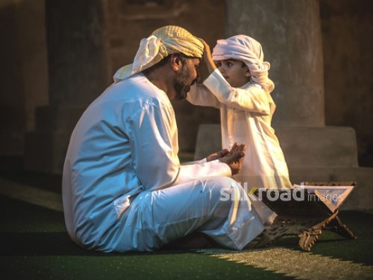Boy fixing traditional outfit of old man|-