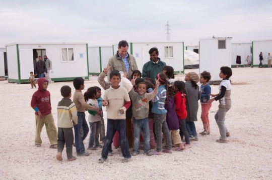 Group of kids showing V sign with men from Zaatari refugee camp for Syrian refugees