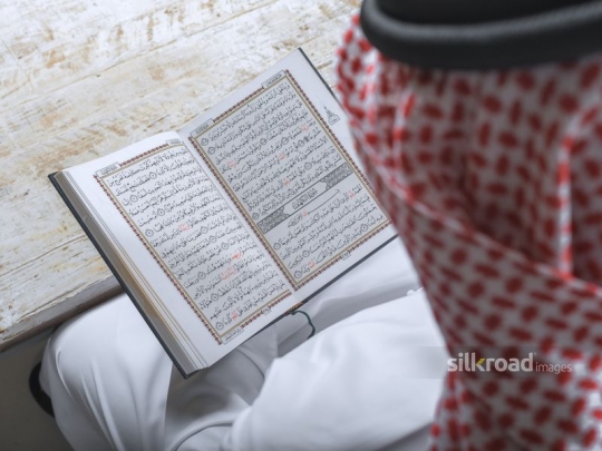 Over the shoulder shot of an Arab man reading the Quran