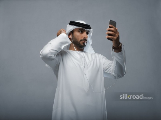 Arabian man looking at himself through his mobile
