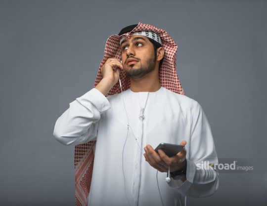 Middle Eastern man fixing his earphones|