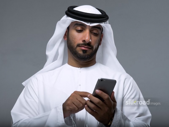 Medium shot of a Middle Eastern using his mobile|