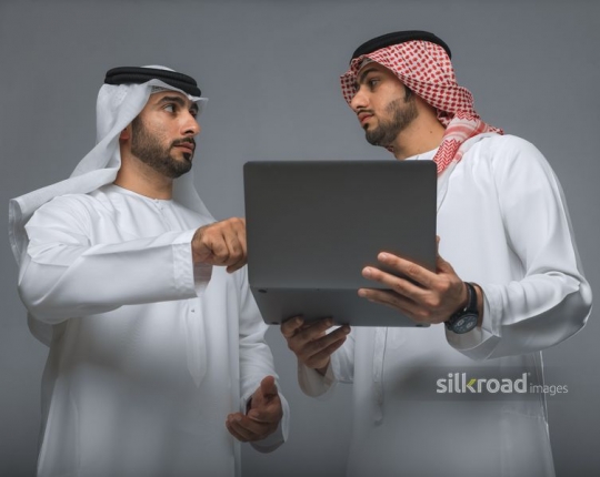 Middle Eastern Businessmen using the device|
