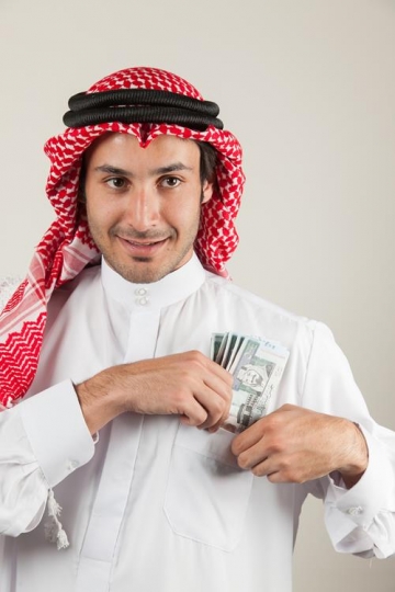 an arabian man putting money in his pocket