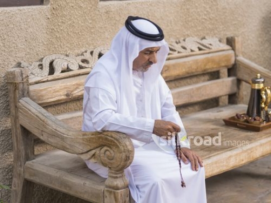 Arab man sitting on the bench with a misbahah in his hand|-