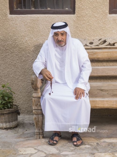 Middle Eastern man sitting on the bench with a misbahah in his hand|-