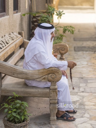 Arab man sitting on the bench with a misbahah in his hand|-