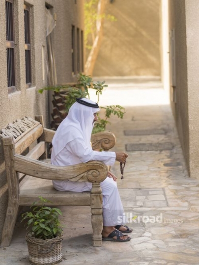 Arab man sitting on the bench traditionally dressed|-
