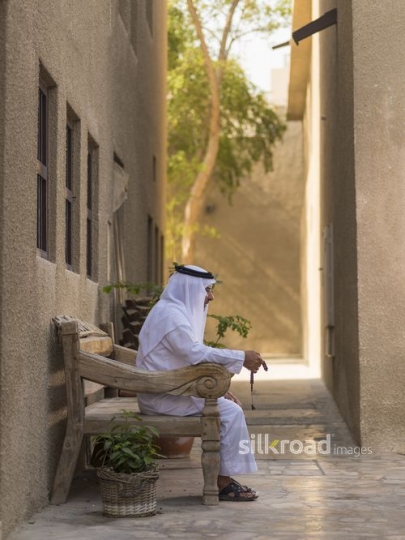 Arab man sitting on the bench traditionally dressed|-