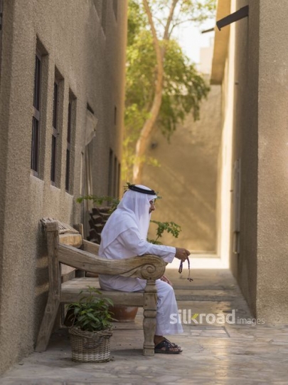 Arab man sitting on the bench holding onto a misbahah|-