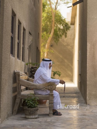 Middle Eastern man sitting on the bench holding onto a misbahah |-