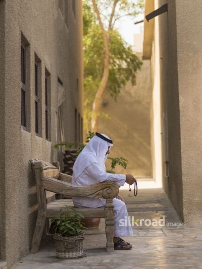 Middle Eastern man traditionally dressed sitting on the bench|-