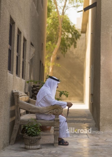Arab man sitting on the bench traditionally dressed|-