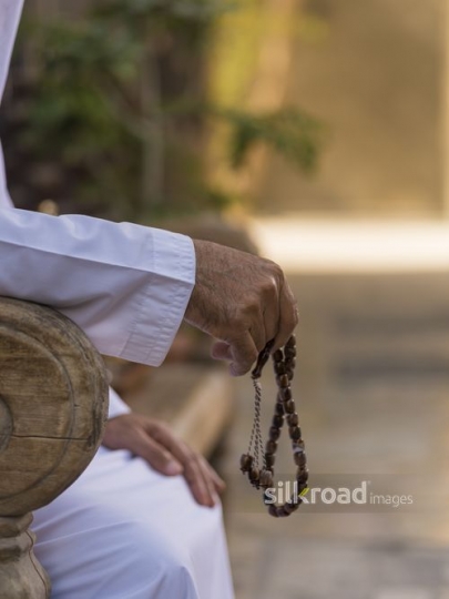 Close up of an arab mans hand holding a misbahah|-