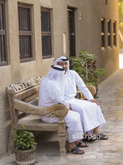 Two arab men sitting on the bench talking to each other|-