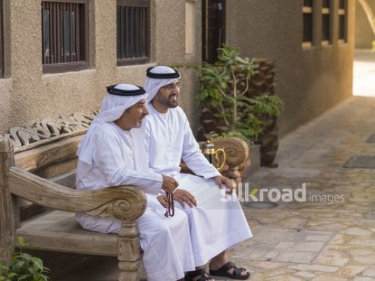 Arab grandfather and father sitting next to each other|-