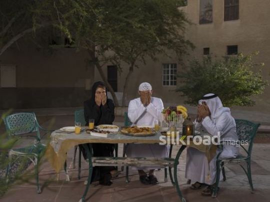REPLACE - Arab family traditionally dressed praying before Iftar|-