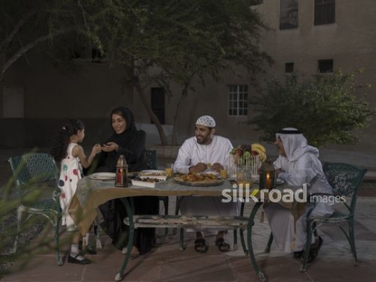 REPLACE - Arab woman talking to the little girl while sitting with the two men on the table|-