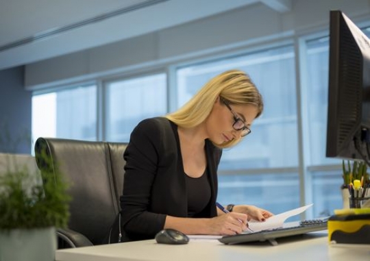 Western business woman sitting by her cubicle working|