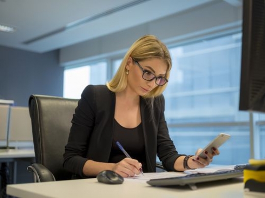 Woman at the office using her mobile and working|