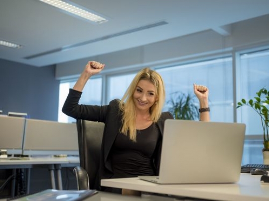Business woman sitting by her desk excited|
