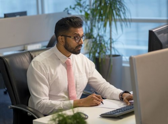 Expat businessman at the office sitting by desk|