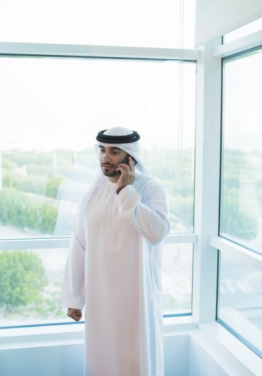 Business man standing by the window making a phone call|-