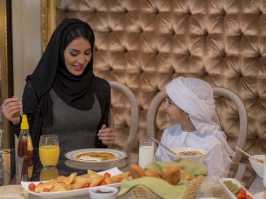 Arab woman sitting with her son having breakfast|-