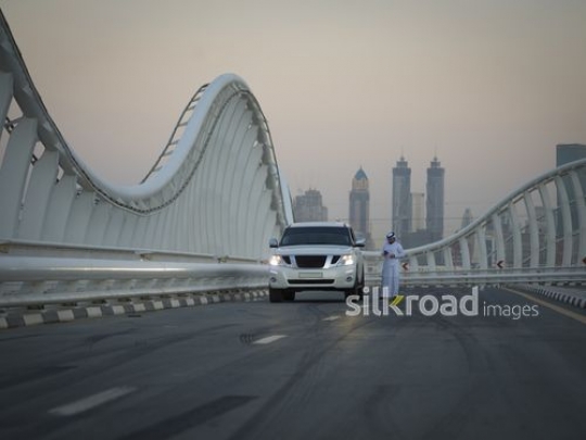 Arab man standing by his car using his phone|-