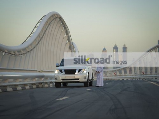 Middle Eastern man standing by the car|