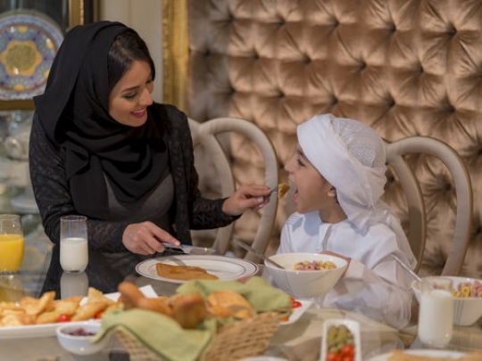 Arabian mother feeding her little son|-