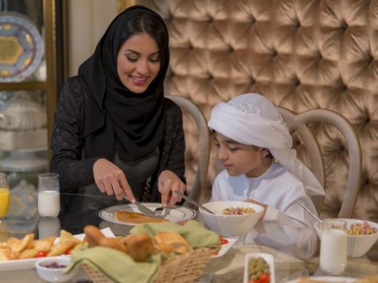 Arab woman cutting the pancake for the little boy|-