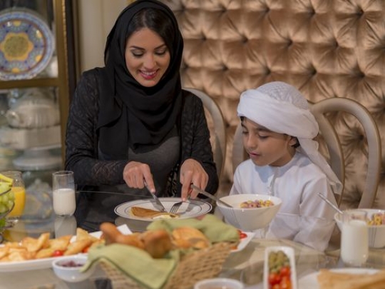 Arab mother cutting the pancake for her son|-