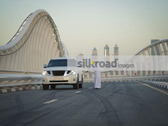 Middle Eastern man dressed in the traditional attire talking on the phone|