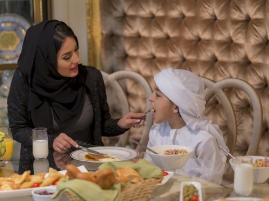 Arab mother feeding her son food|-