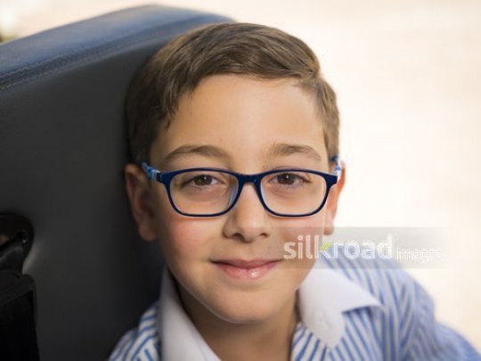Close up of a Middle Eastern kid wearing blue glasses|-