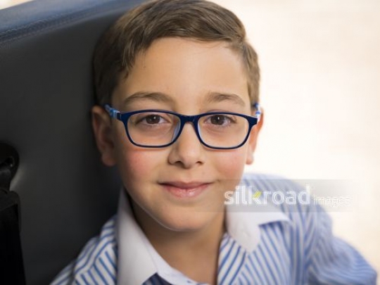 Close up of a Middle Eastern boy wearing glasses|-