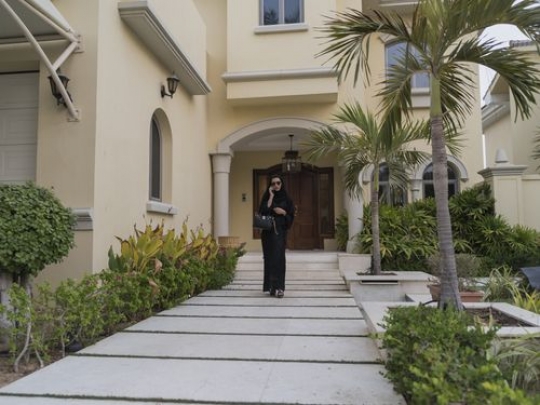 Arab woman on the phone leaving the house|-