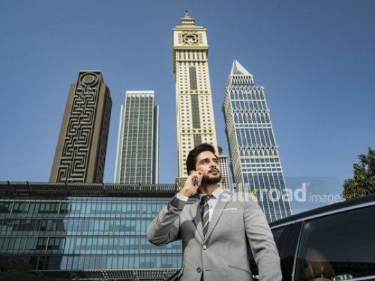 Businessman standing dressed in a grey suit using his phone|-