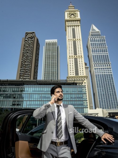 Businessman leaning on his car using his phone|-