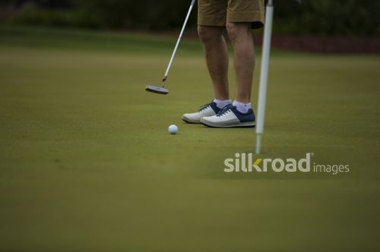 A man playing golf is about to score |-