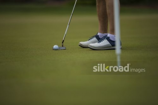 Man playing golf lines up his putt and is preparing to play